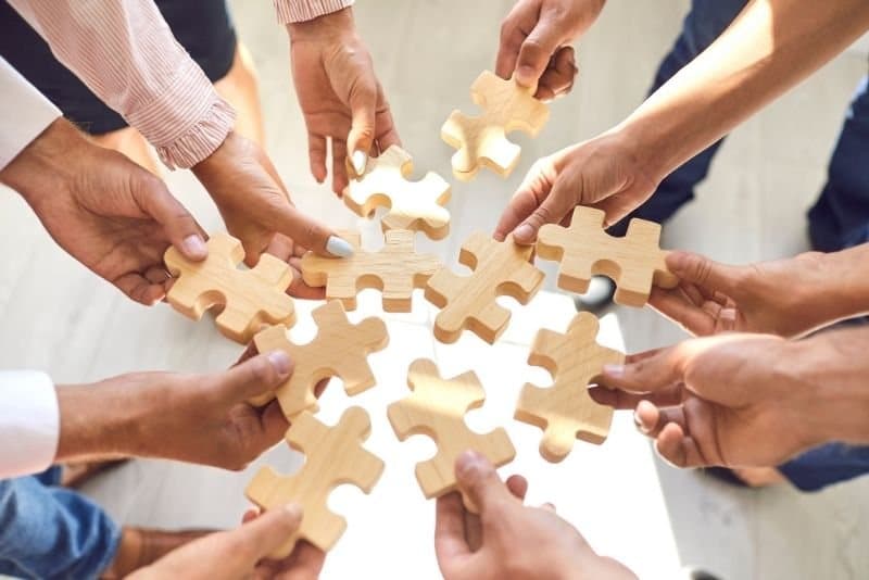 Teamarbeit: Hände eines Teams fügen Puzzleteile zusammen